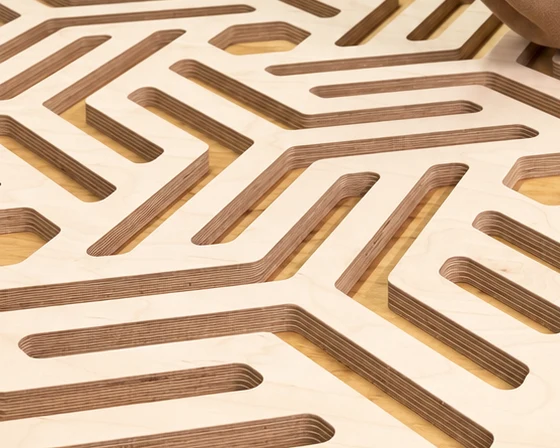 Close-up of a CNC-cut plywood panel, the layers of the plywood visible in every cut edge